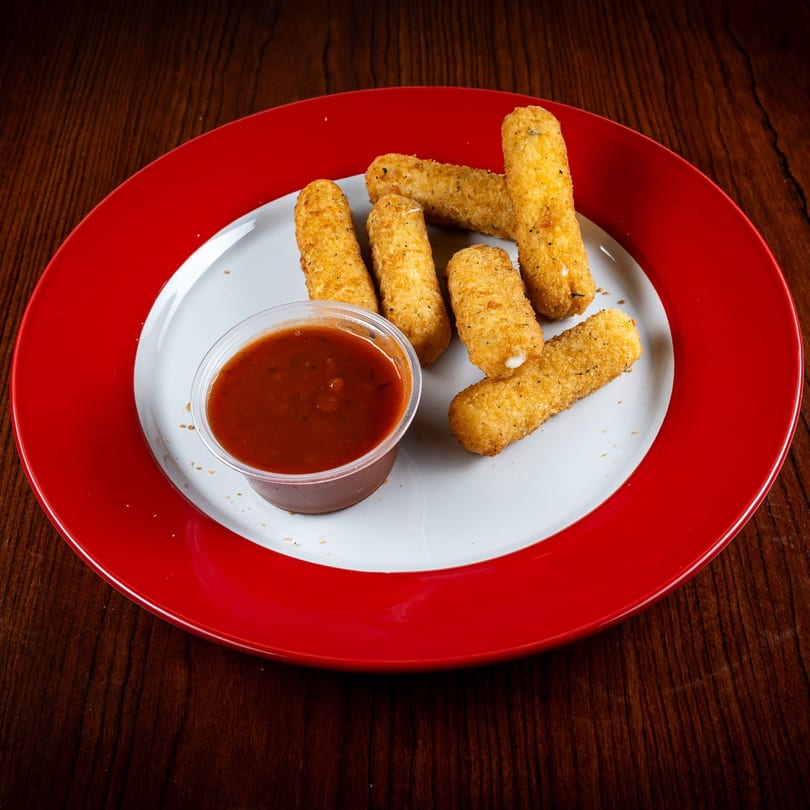 Golden-brown mozzarella sticks with a side of marinara sauce on a white and red plate.