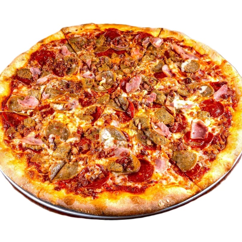 A whole GoGo Pizza with pepperoni, sausage, ham, and bacon on a metal pizza pan.